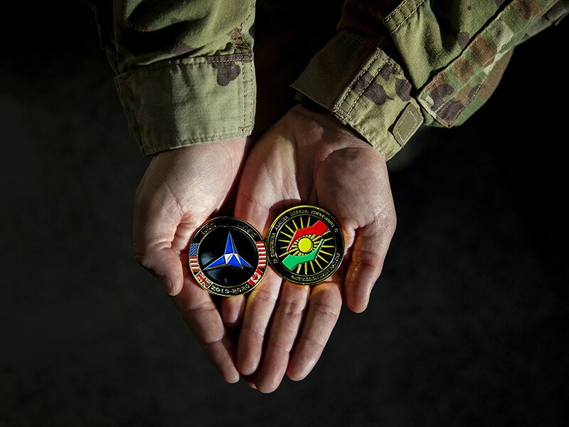 Moneda conmemorativa (challenge coin) que simboliza la alianza militar entre el Centro de Coordinación del Kurdistán (KCC) y el KRSC en la Base Aérea de Erbil, Irak.